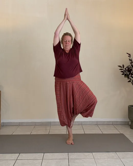 Yoga teacher in tree pose, hands above her head, between two floor lamps at Studio Sonnenaufgang