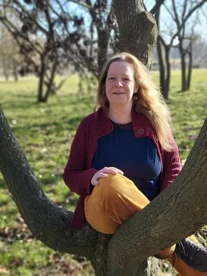 Andrea Neufeldt, yoga teacher at Studio Sonnenaufgang, portrait by a tree in the green