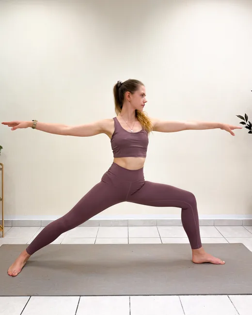 Yoga teacher in warrior II with arms stretched wide on the mat at Studio Sonnenaufgang